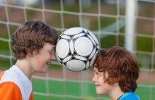 Bild zeigt zwei Kinder die einen Ball zwischen den Köpfen haben; Schaltfläche zur Ganztagsentwicklung