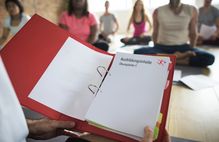 Bild zeigt eine Kladde mit Zetteln; Schaltfläche zu Praxishilfen für Kooperationen Schule und Verein