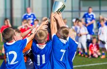Bild zeigt Kinder-Fußballmannschaft mit Pokal; Schaltfläche zum Kooperationspreis Sportverein und Schule