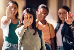 Sexismus im Sport & Ehrenamt Vier Frauen zeigen mit ausgestreckter Hand eine Stopp-Geste.