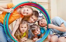 Bild zeigt Kinder, die durch einen Reifen schauen; Schaltfläche zum Fachtag Bewegung in Kita, Schule und Verein